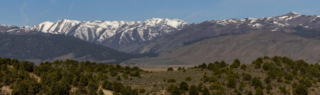 Tranquil mountain terrain with snow-capped peaks and a serene stream foreground.