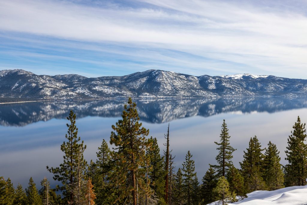 Serene view of snow-capped mountains reflecting in the calm waters of Lake Tahoe.